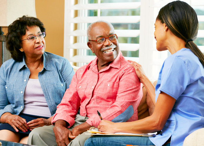 caregiver happily talking to old couple